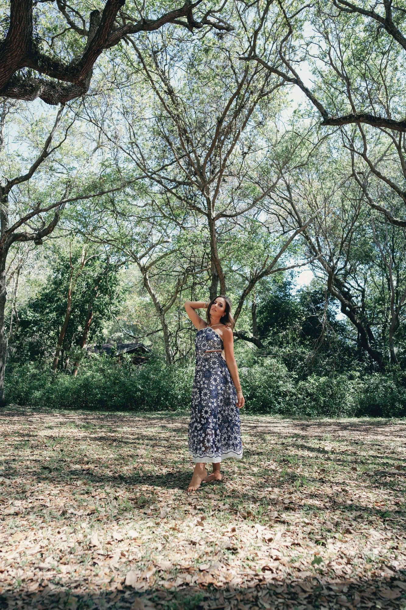 Reign — Charlotte in a flowing floral dress standing serenely in a sunlit grove, embodied and self-possessed