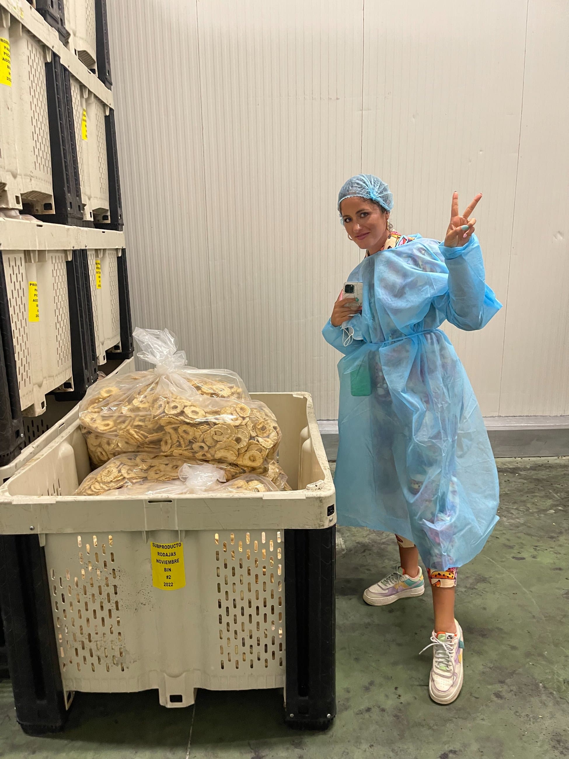 Root — Charlotte on the production floor beside a bin of naturally dried fruit, where nourishment begins